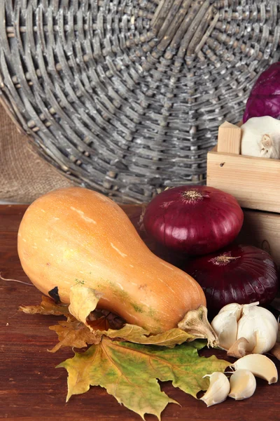 Verschillende groenten in vak met de gele bladeren op tafel op rieten achtergrond — Stockfoto