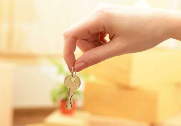 Main féminine avec clés ob pile de cartons fond : déménagement concept de maison — Photo