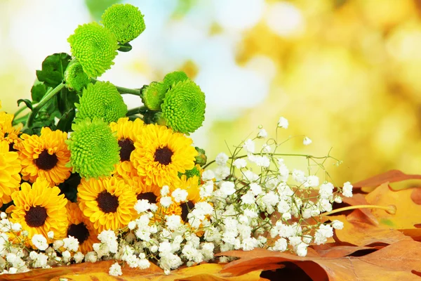 Krásné květy se žlutými listy na stole na světlé pozadí — Stock fotografie