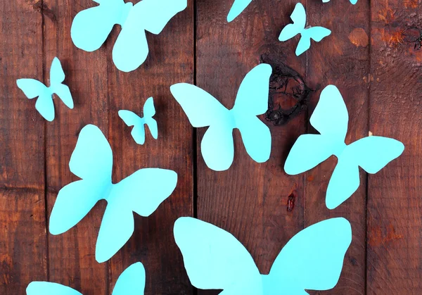 Papel azul mariposas sobre fondo tablero de madera — Foto de Stock