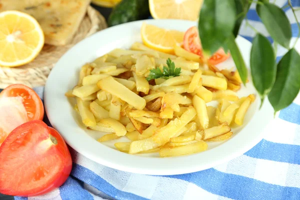 Ruddy fried potatoes on plate on tablecloth close-up — Stock Photo, Image