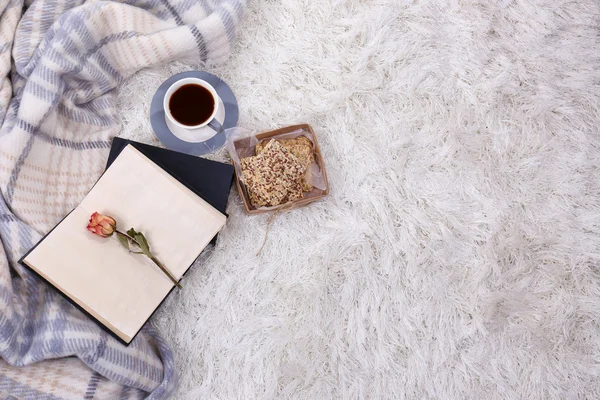 Composición con cuadros calientes, libro, taza de bebida caliente sobre fondo de alfombra de color —  Fotos de Stock