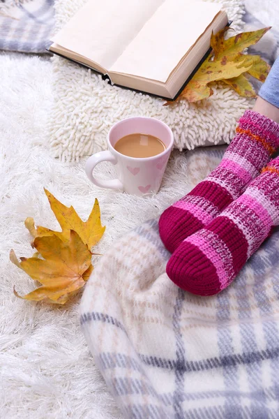 Sıcak şal, kitap, sıcak içecek ve renk Halı zemin üzerine kadın bacağı bardak ile kompozisyon — Stok fotoğraf