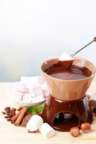 Fondue de chocolate con caramelos de malvavisco, sobre mesa de madera, sobre fondo claro — Foto de Stock