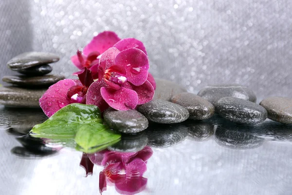 Composición con hermosa orquídea floreciente con gotas de agua y piedras de spa, sobre fondo de color claro — Foto de Stock