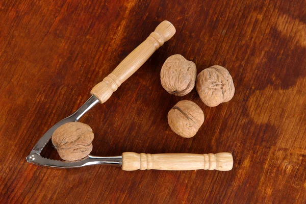 Nussknacker mit Nüssen auf Holztisch in Großaufnahme — Stockfoto