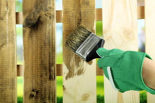 Applying protective varnish to wooden fence, on bright background — Stock Photo, Image