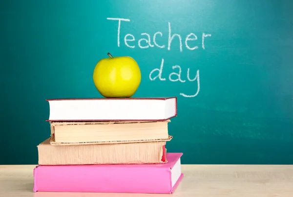 Books and apple on blackboard background with inscription Teacher Day — Stock Photo, Image