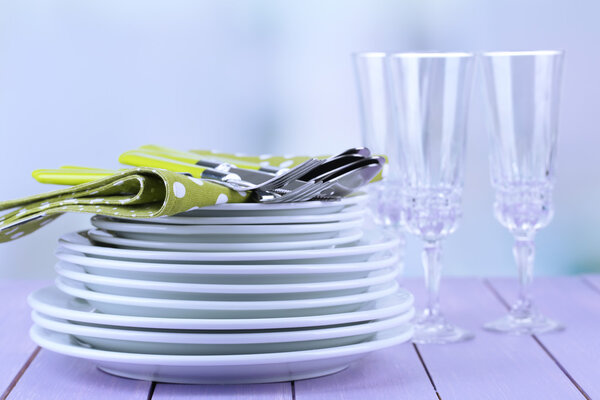 Clean dishes on wooden table on light background