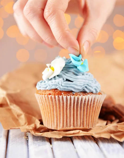 Confeiteiro decoração saboroso cupcake com creme de manteiga, na mesa de madeira cor, no fundo luzes — Fotografia de Stock