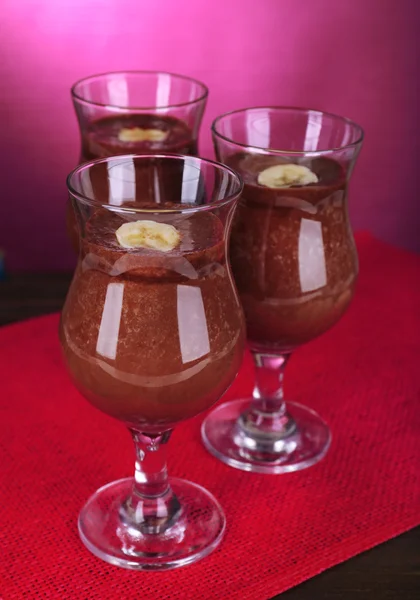 Coquetéis com banana e chocolate na mesa em fundo roxo — Fotografia de Stock