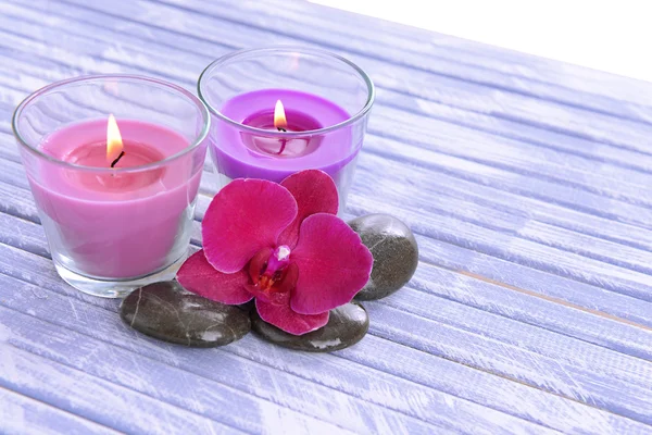 Hermosas velas de colores y flores de orquídea, sobre fondo de madera de color — Foto de Stock