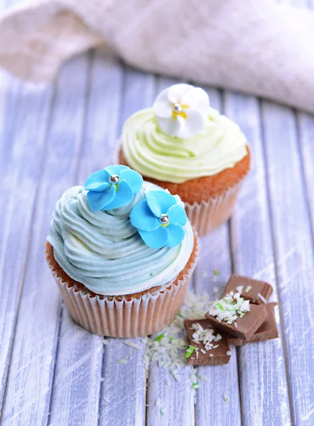 木製の背景の色に、バター クリームとおいしいカップケーキ — ストック写真