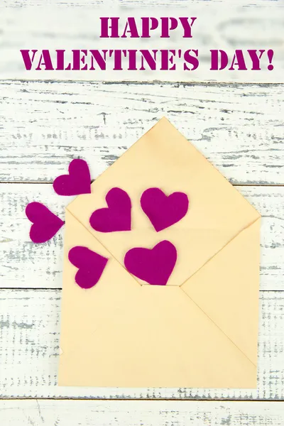 Envelope velho bonito com corações decorativos em fundo de madeira — Fotografia de Stock