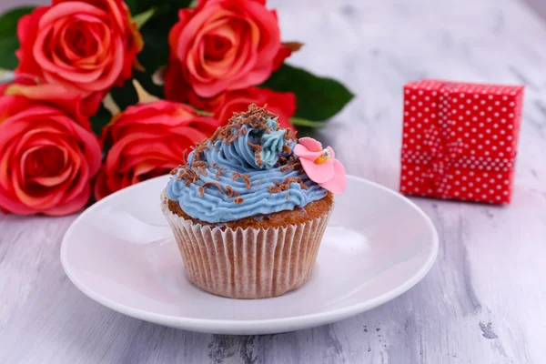 Tasty cupcake with butter cream, on plate, on color wooden background — Stock Photo, Image