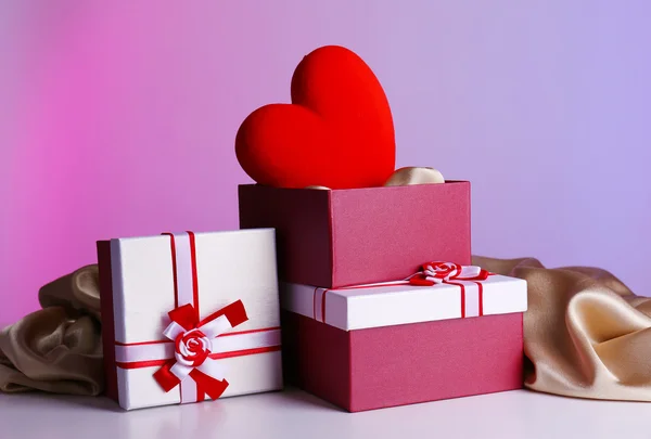 Στοίβα κιβώτια δώρων και διακοσμητικά καρδιά, σε φόντο χρώμα — Φωτογραφία Αρχείου