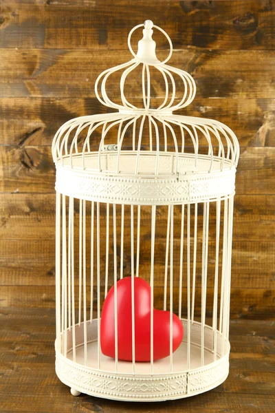 Heart in decorative cage on wooden background — Stock Photo, Image