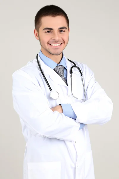 Médico masculino em pé sobre fundo cinza — Fotografia de Stock