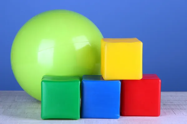 Bola brillante y cubos de colores en la mesa sobre fondo azul — Foto de Stock