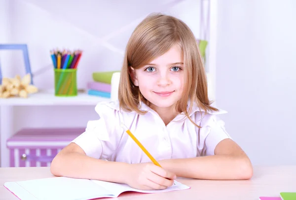 Niña sentada en el escritorio en la habitación —  Fotos de Stock