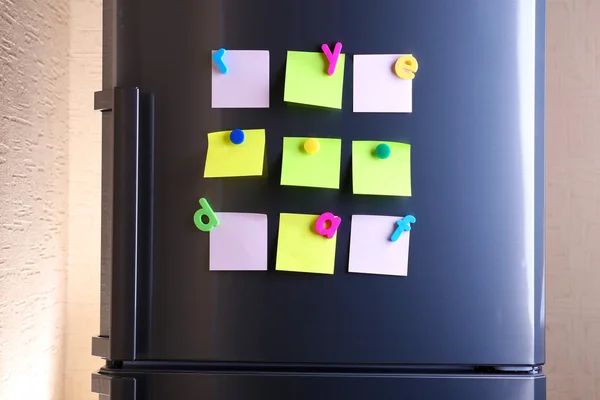 Empty paper sheets and colorful magnets on fridge door — Stock Photo, Image