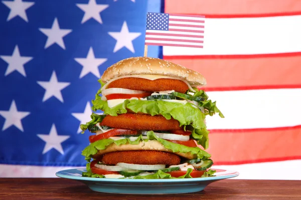 米国旗の背景のカラー プレート上の巨大なハンバーガー — ストック写真