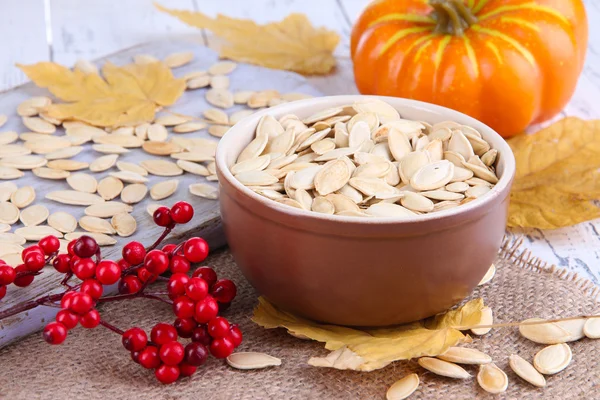 Pumpkin seeds in bowl with pumpkin on table close up — Stock Photo, Image