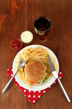 patates kızartması ve ahşap zemin üzerinde soğuk içecek ile lezzetli peynirli burger