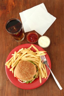 patates kızartması ve ahşap zemin üzerinde soğuk içecek ile lezzetli peynirli burger