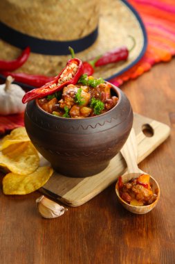 Chili Corn Carne - traditional mexican food, in pot, on napkin, on wooden background clipart