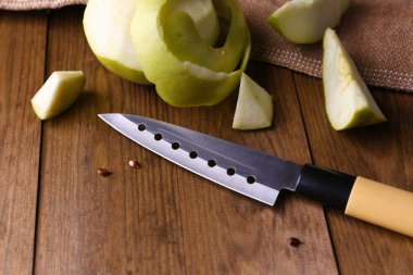Mutfak bıçağı ve yeşil elma, ahşap arka planda.