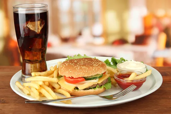 Sabrosa hamburguesa con patatas fritas y bebida fría, sobre fondo brillante —  Fotos de Stock