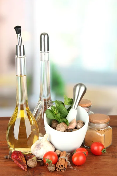 Composition of mortar, bottles with olive oil and vinegar, and green herbals, on bright background — Stock Photo, Image