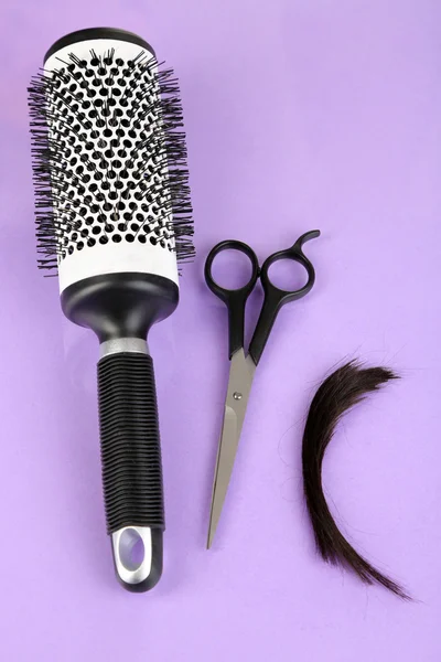 Trozos de cabello cortado con tijeras sobre fondo morado — Foto de Stock