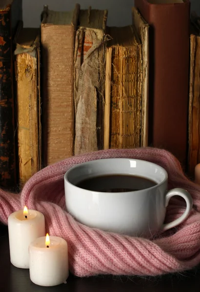 Taza de café envuelto en bufanda sobre fondo de libros — Foto de Stock