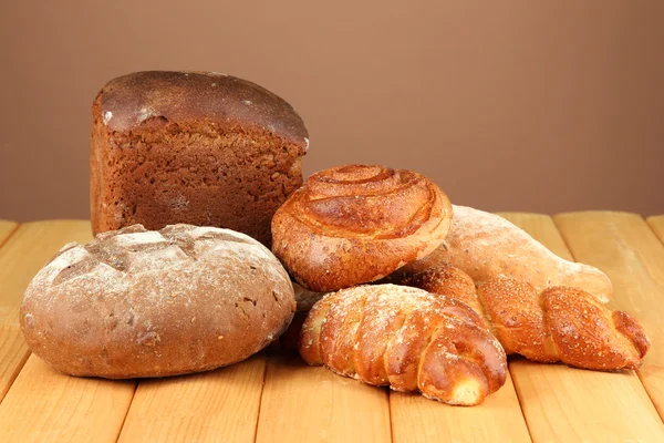 Composition with bread and rolls on wooden table, on color background — Stock Photo, Image