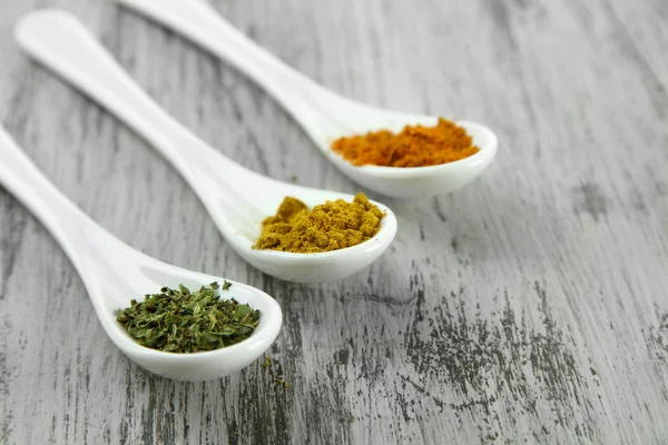 Assortment of spices in white spoons, on wooden background — Stock Photo, Image