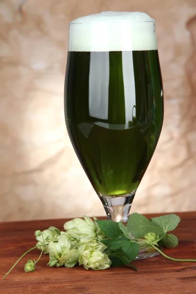 Sklo zelené piva a chmele, na dřevěný stůl — Stock fotografie