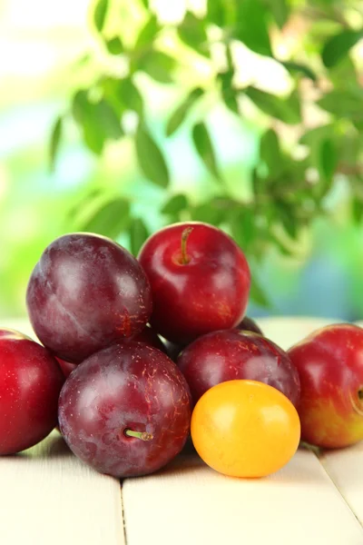 Ripe plums on wooden table on natural background — Stock Photo, Image