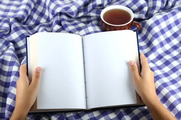 Livro em mãos sobre fundo xadrez — Fotografia de Stock