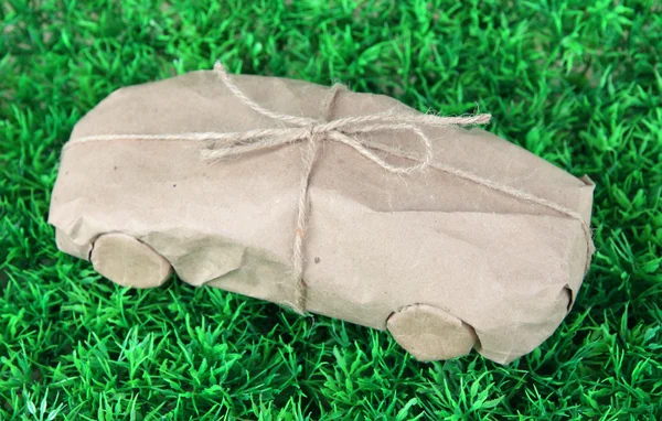 Coche envuelto en papel kraft marrón, sobre fondo de hierba verde —  Fotos de Stock