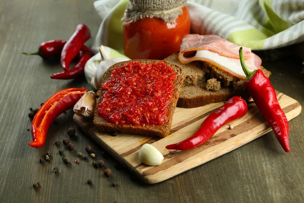 Složení s tomatovou salsou o chlebu,, red hot chili papričky a česnek, na ubrousek, na dřevěné pozadí — Stock fotografie
