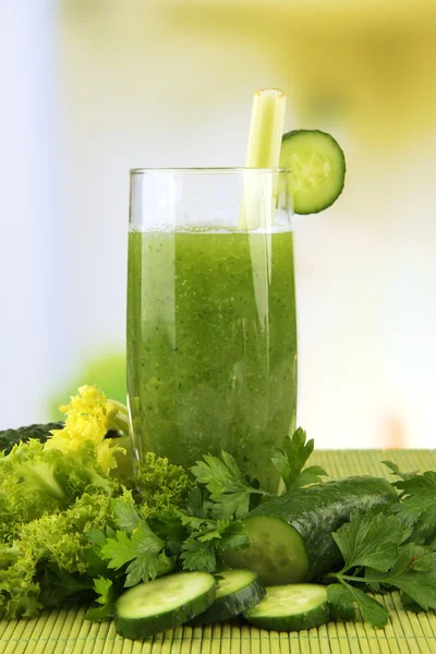 Glass of green vegetable juice and vegetables on bamboo mat on bright background — Stock Photo, Image