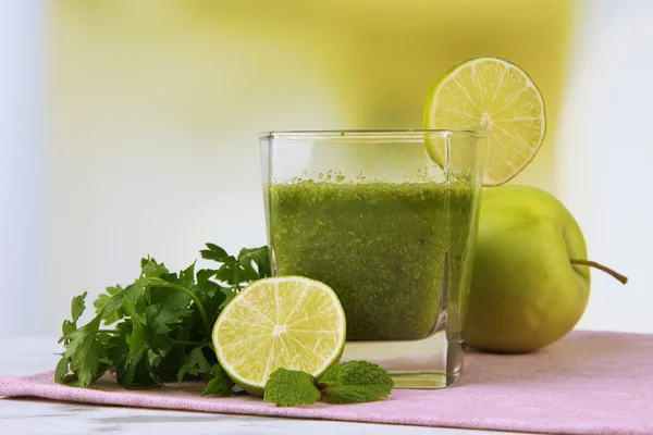 Glass of green vegetable juice on wooden table on bright background — Stock Photo, Image