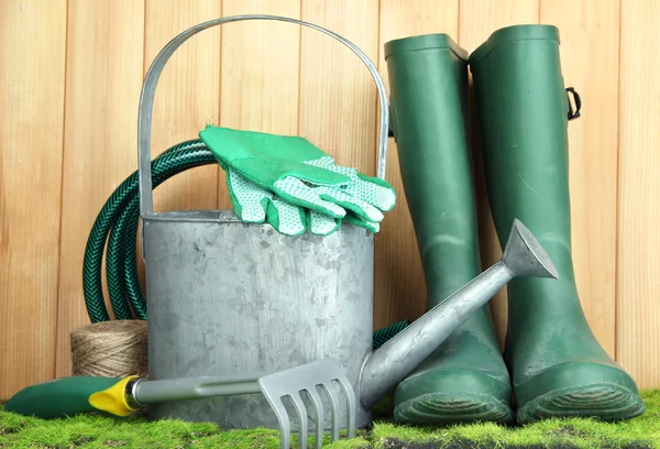 Gardening tools on grass on wooden background — Stock Photo, Image