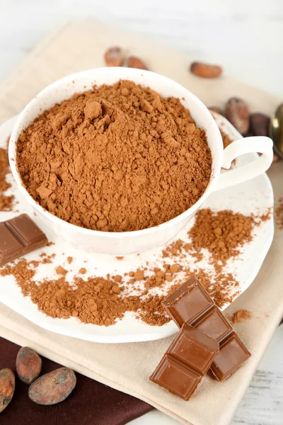 Cacao en polvo en taza en servilleta sobre mesa de madera — Foto de Stock