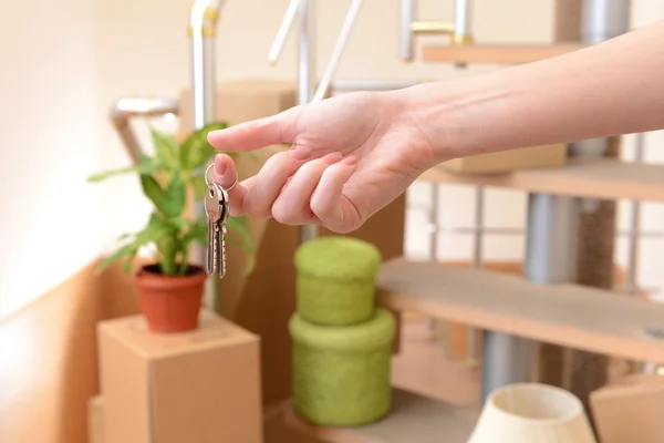 Mano femminile con chiavi ob pila di cartoni sfondo: concetto di casa in movimento — Foto Stock