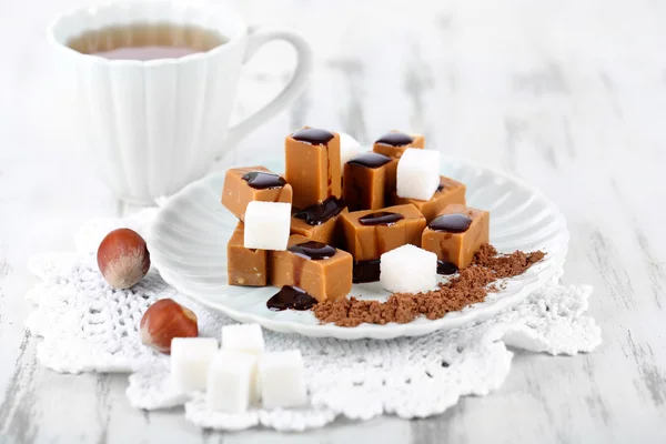Πολλά ζαχαρωτά σε πιάτο και φλιτζάνι τσάι σε χαρτοπετσέτα στο ξύλινο τραπέζι — Φωτογραφία Αρχείου