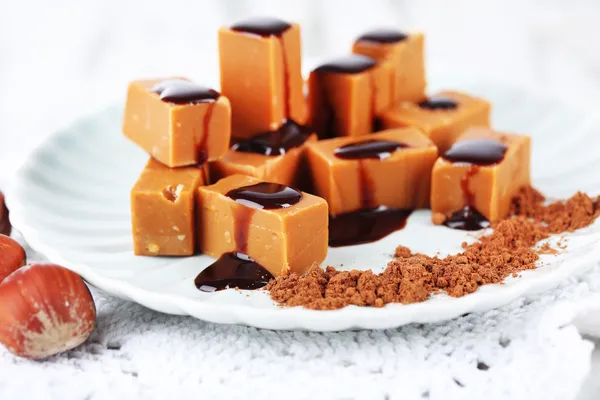 Many toffee on plate on napkin on wooden table — Stock Photo, Image