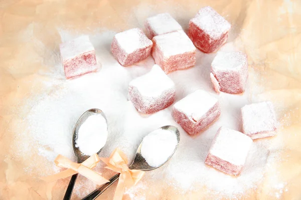 Tasty oriental sweets (Turkish delight) with powdered sugar, on brown background — Stock Photo, Image